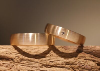 zeitlos elegante Trauringe in Rotgold, ein kleiner Diamant mit Brillantschliff im Damenring