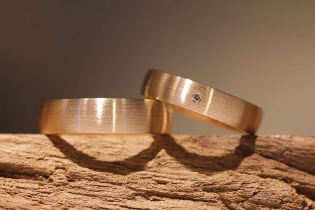 zeitlos elegante Trauringe in Rotgold, ein kleiner Diamant mit Brillantschliff im Damenring