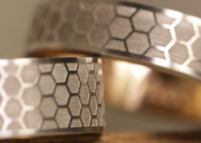 Trauringe in Platin mit Rotgold und Lasergravur außen Wabenmuster innen Schrifttypo