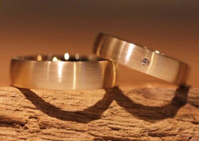 Schlichte laengsmatte Eheringe aus 585er Rosegold Damenring mit weissen Diamant