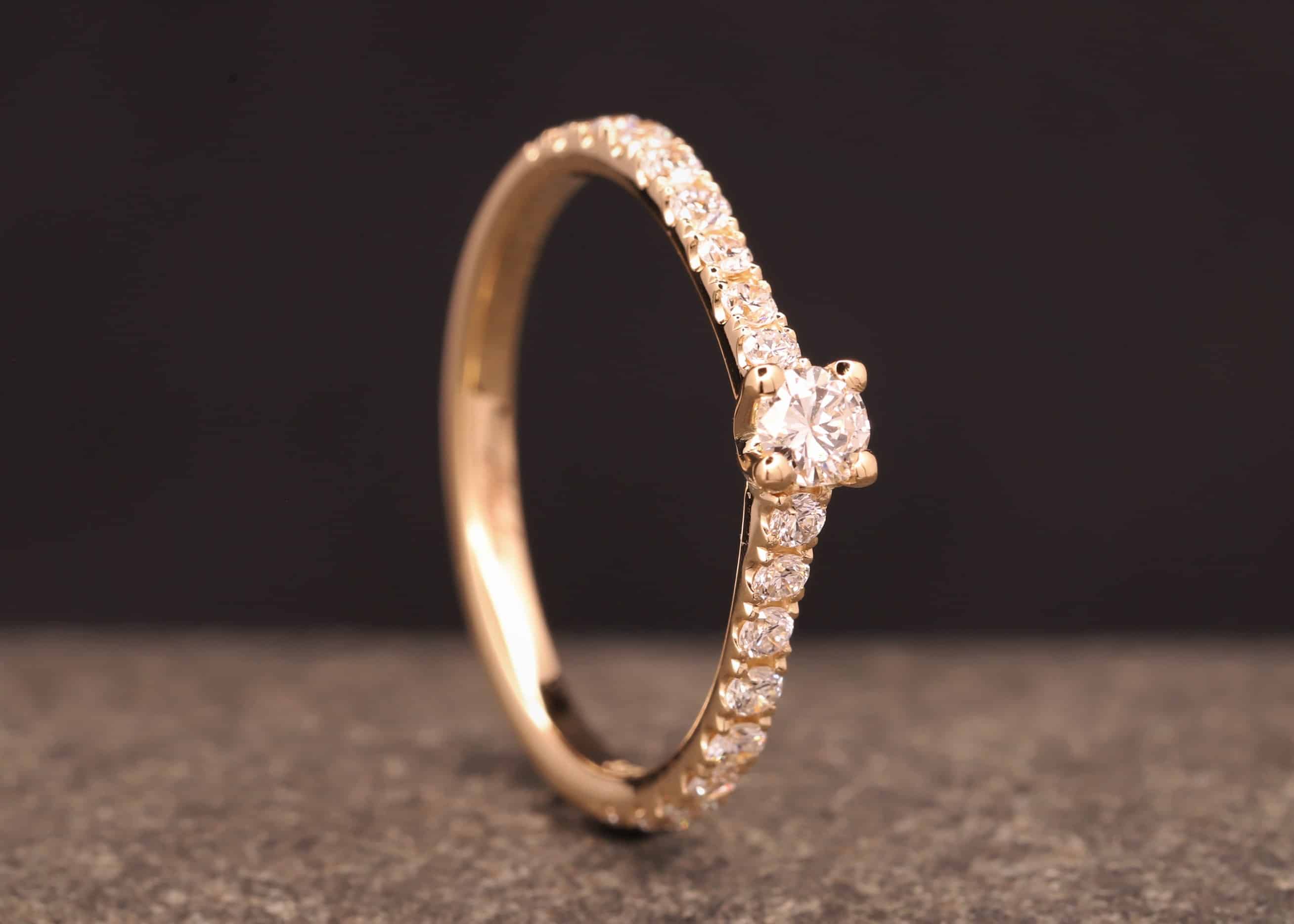 verlobungsring in rose gold mit großen diamant und kleinen diamanten in der ringschiene