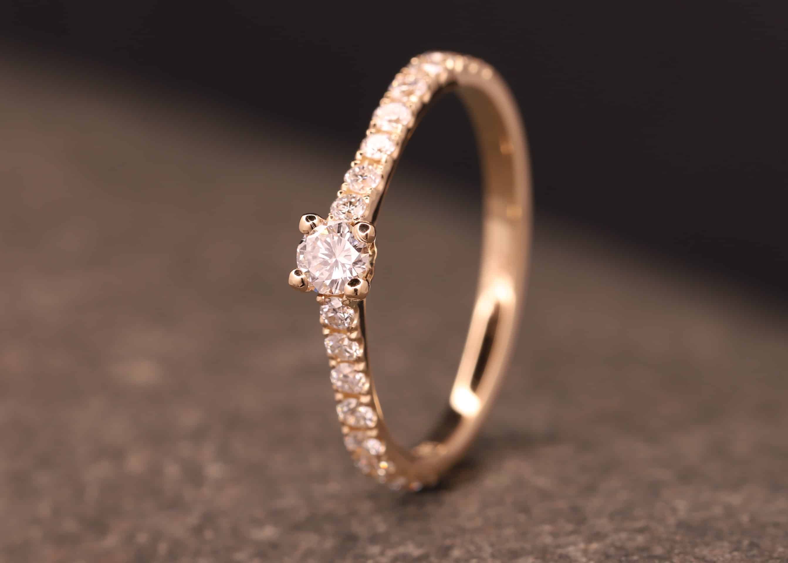verlobungsring in rose gold mit großen diamant und kleinen diamanten in der ringschiene